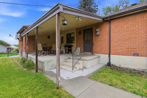 View of front of house featuring covered porch, brick siding, and a front yard