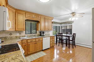Kitchen with light stone countertops, a ceiling fan, decorative backsplash, and plenty of natural light