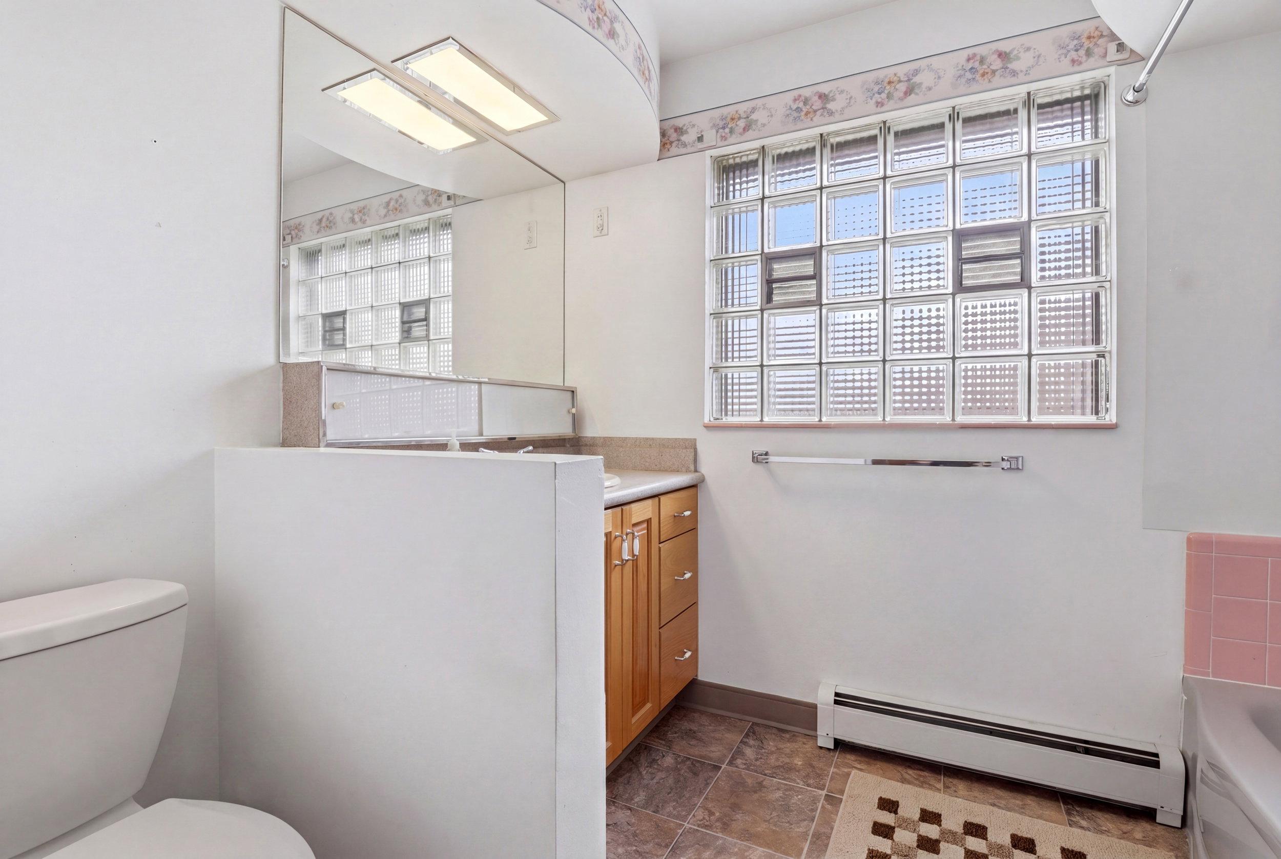 Full bathroom with vanity, baseboard heating, and a tub to relax in