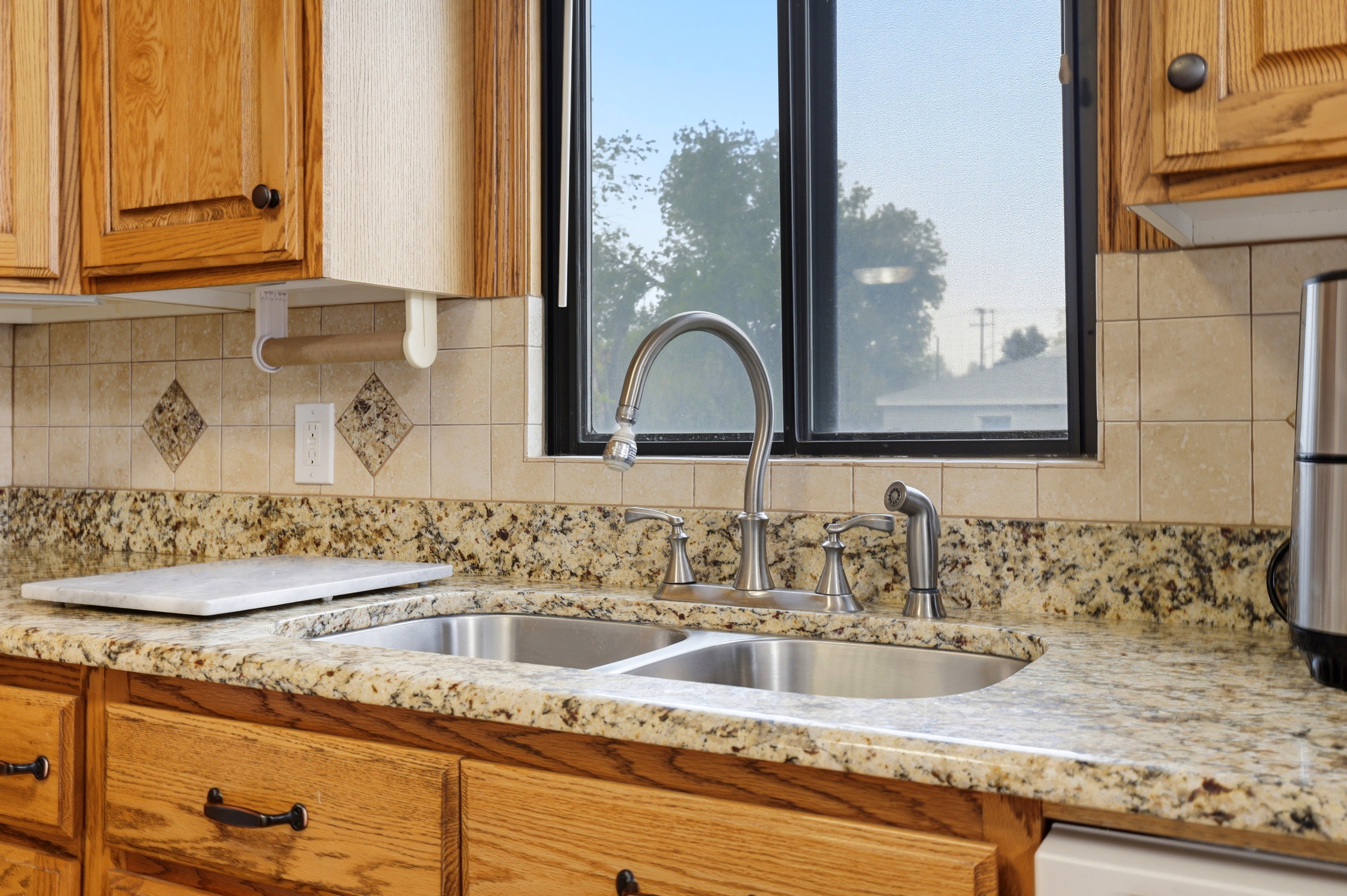 Kitchen with wood finish cabinetry, light stone countertops, and decorative backsplash