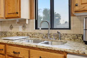 Kitchen with wood finish cabinetry, light stone countertops, and decorative backsplash