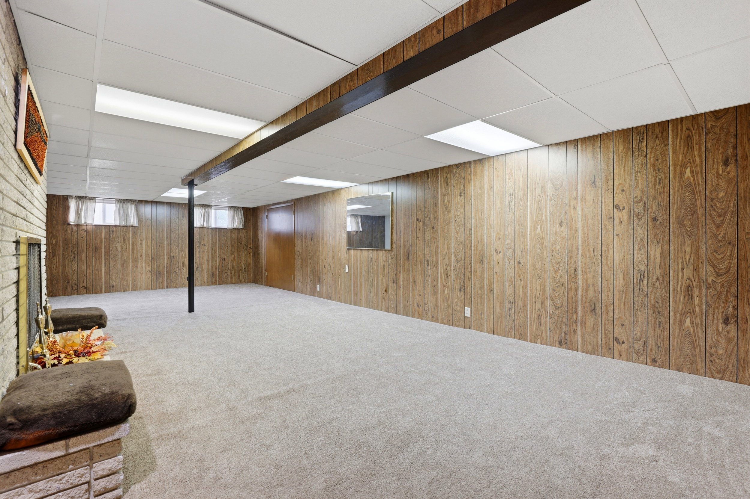 Below grade area featuring a drop ceiling, carpet floors, and wooden walls
