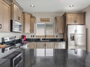 Kitchen featuring stainless steel appliances, dark stone countertops, and recessed lighting
