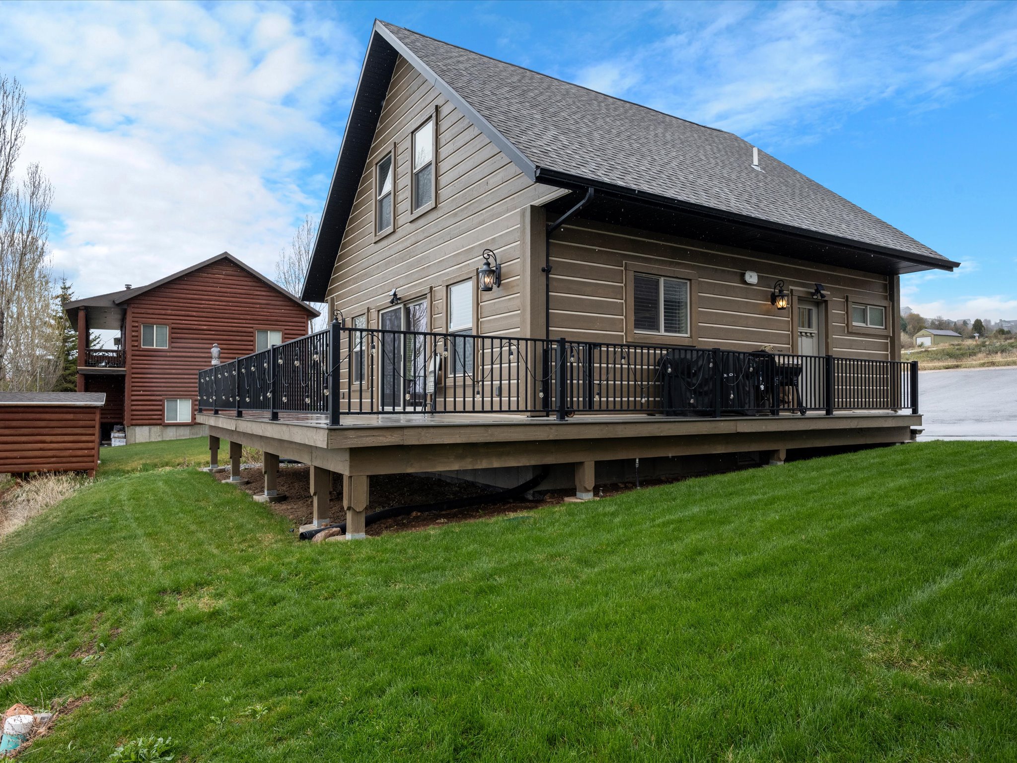 Rear view of property featuring a yard, a wooden deck, and a shingled roof