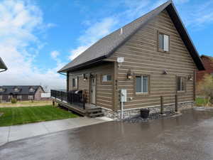 View of property exterior featuring a deck, a lawn, and a shingled roof