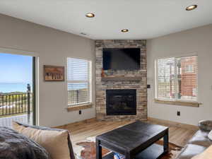 Living area with wood finished floors, a stone fireplace, and recessed lighting