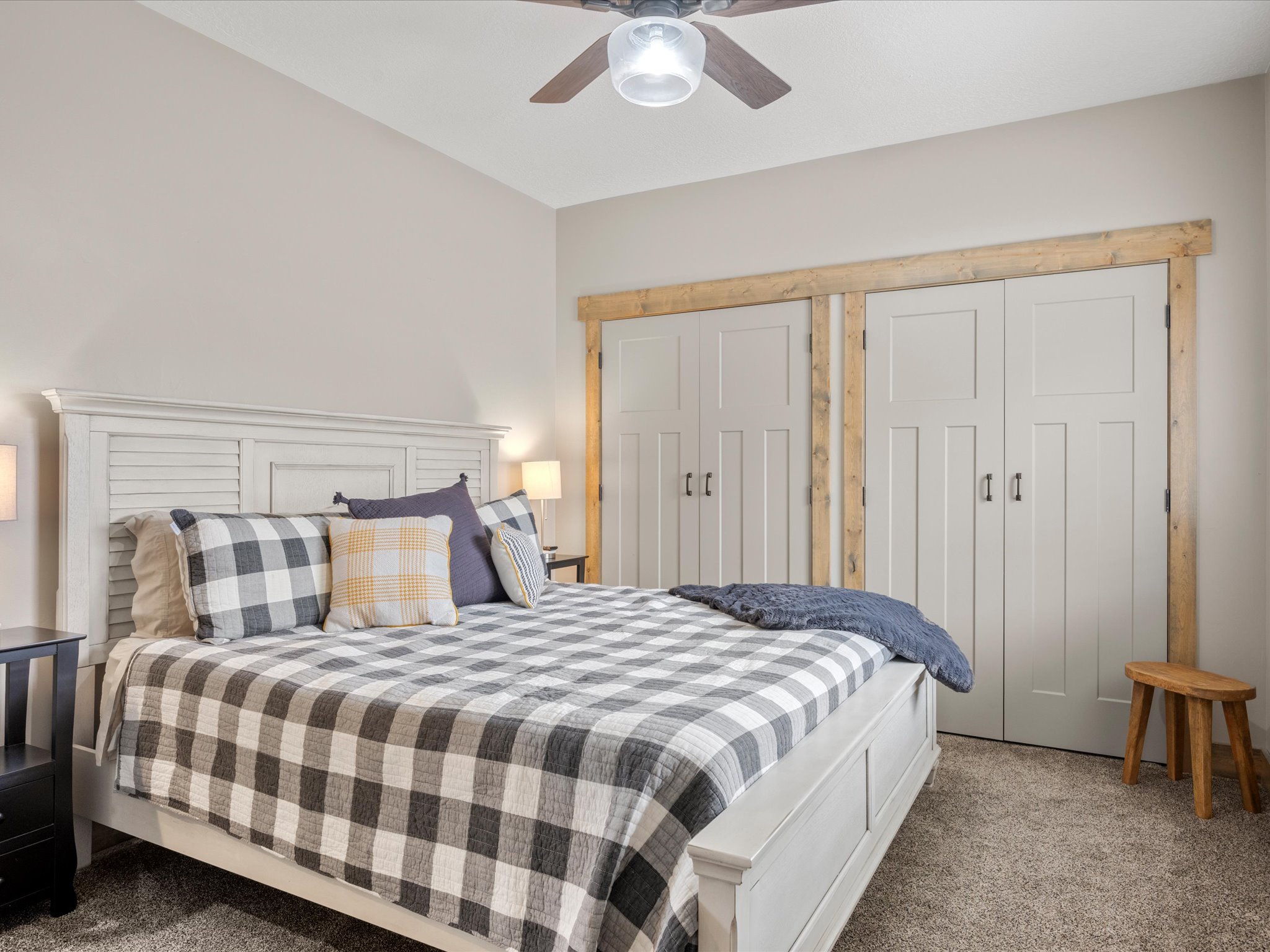 Carpeted bedroom with a ceiling fan and two closets