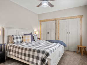 Carpeted bedroom with a ceiling fan and two closets