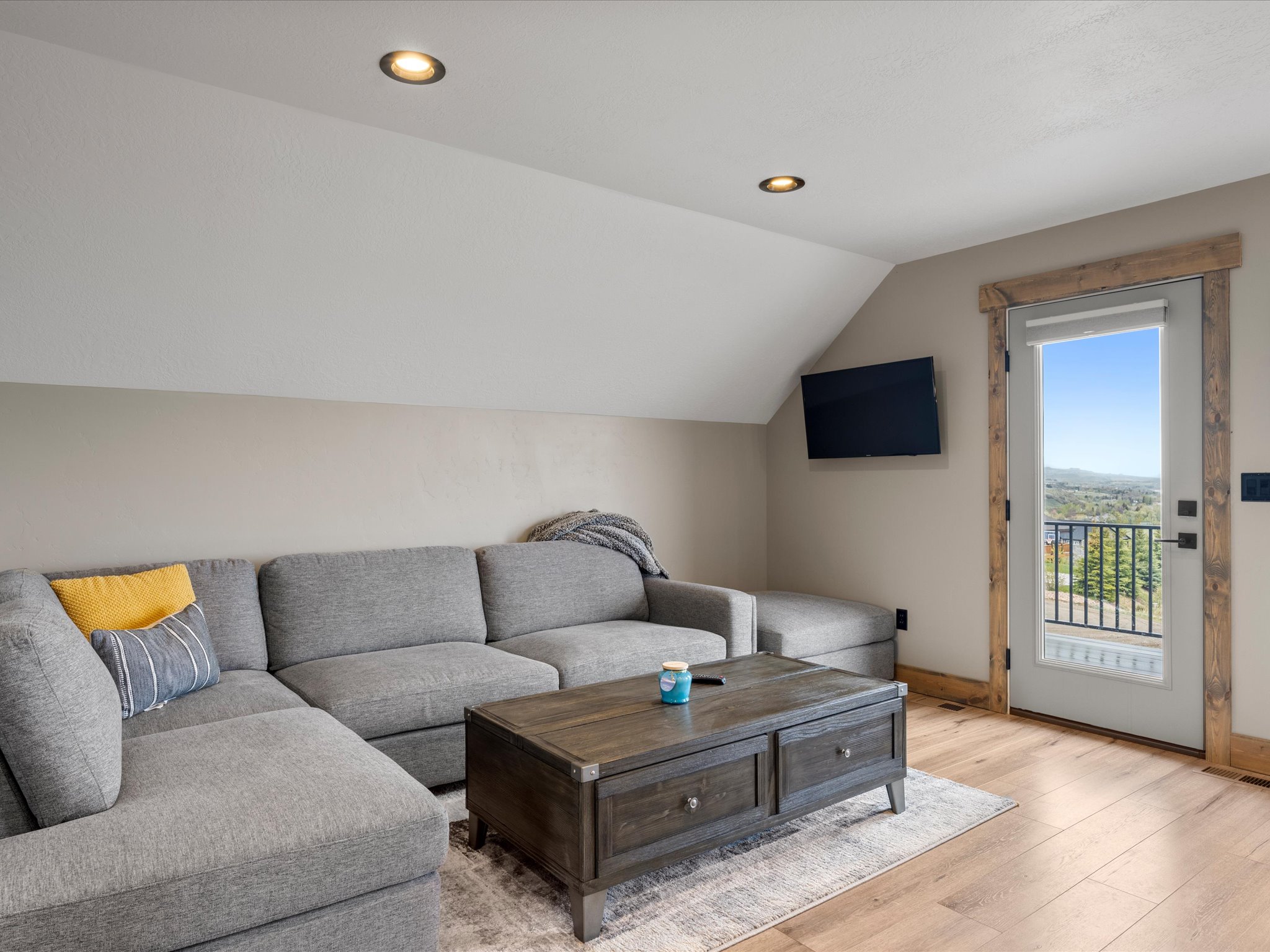Living room with light wood-style flooring, lofted ceiling, and recessed lighting