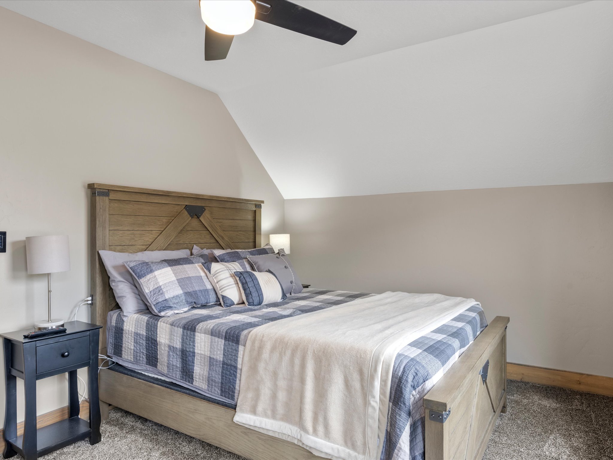 Carpeted bedroom with vaulted ceiling and a ceiling fan