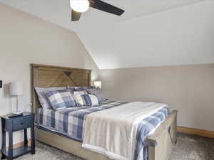 Carpeted bedroom with vaulted ceiling and a ceiling fan