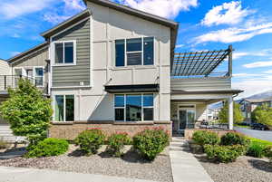 View of front of home featuring brick siding, a porch, stucco siding, and board and batten siding with the primary walkout to the patio entrance area