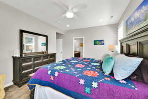 Large primary bedroom featuring ceiling fan, ensuite bath, light carpet, and recessed lighting