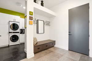 Laundry area with stacked washer and dryer and baseboards