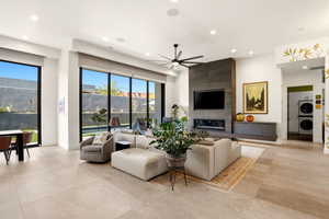 Living room featuring a ceiling fan, stacked washing machine and dryer, recessed lighting, and a large fireplace