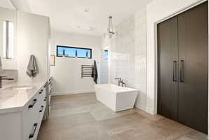 Full bath featuring a soaking tub, vanity, and recessed lighting