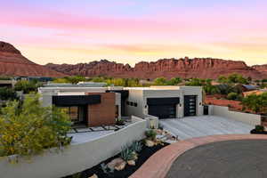 Modern home featuring a garage, a mountain view, concrete driveway, and a fenced front yard
