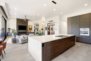 Kitchen with modern cabinets, a kitchen island, stainless steel appliances, light stone counters, and a ceiling fan