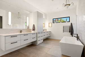 Full bathroom featuring a freestanding bath, two vanities, and backsplash
