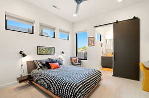 Bedroom with a barn door, ensuite bathroom, and recessed lighting