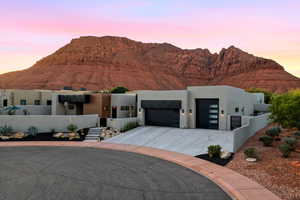 View of front of property featuring a garage, a mountain view, stucco siding, and concrete driveway