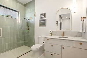 Full bath featuring vanity, a tile shower, and backsplash