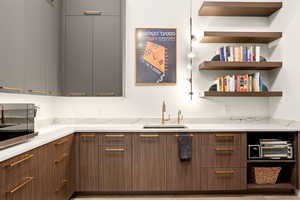 Kitchen featuring modern cabinets, open shelves, stainless steel microwave, and light stone counters