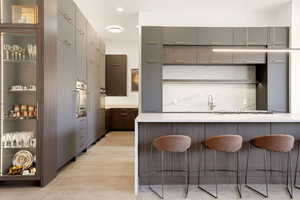 Kitchen with a kitchen breakfast bar, gray cabinets, open shelves, oven, and modern cabinets
