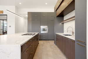 Kitchen with modern cabinets, stainless steel appliances, light stone counters, recessed lighting, and backsplash