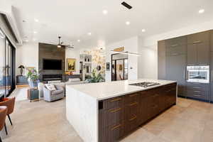 Kitchen with modern cabinets, a center island, stainless steel appliances, a ceiling fan, and light stone counters