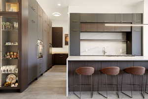 Kitchen with a breakfast bar area, open shelves, stainless steel appliances, modern cabinets, and gray cabinets