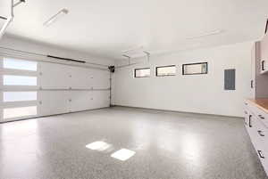 Garage featuring electric panel and baseboards