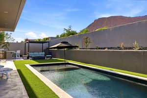 View of pool featuring an outdoor living space, a fenced backyard, patio surround, area for grilling, and a mountain view