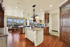 Dual tone kitchen featuring two tone cabinets, dark wood finished floors, light stone countertops, arched walkways, and hanging light fixtures