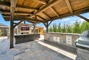 View of patio with an outdoor stone fireplace and an outdoor kitchen with living area