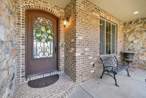 Entrance to property featuring brick siding and a porch