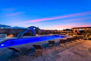 View of swimming pool featuring a water slide, a fenced backyard, and patio surround