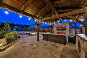 Fenced backyard with an outdoor living space with a fireplace and a patio area