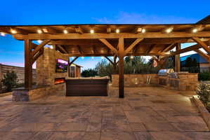 View of patio / terrace featuring an outdoor stone fireplace and an outdoor kitchen with living area