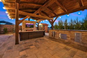 View of patio / terrace featuring an outdoor stone fireplace and an outdoor kitchen and area to lounge