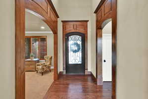 Entrance foyer with arched walkways, dark wood-style flooring, crown molding, and recessed lighting