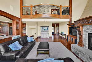 Living area with recessed lighting, a stone fireplace, dark wood finished floors, a high ceiling, and arched walkways