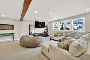 Living area featuring light colored carpet, recessed lighting, and beam ceiling