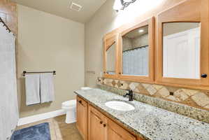 Full bath featuring vanity, curtained shower, light tile patterned flooring, and tasteful backsplash