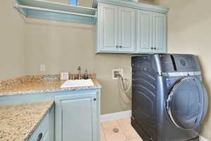 Laundry area with washer / dryer, light tile patterned floors, and cabinet space
