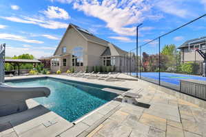 View of pool with patio surround, a water slide, a diving board, and community basketball court