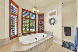 Full bathroom featuring a whirlpool tub, light tile patterned floors, and hanging lights