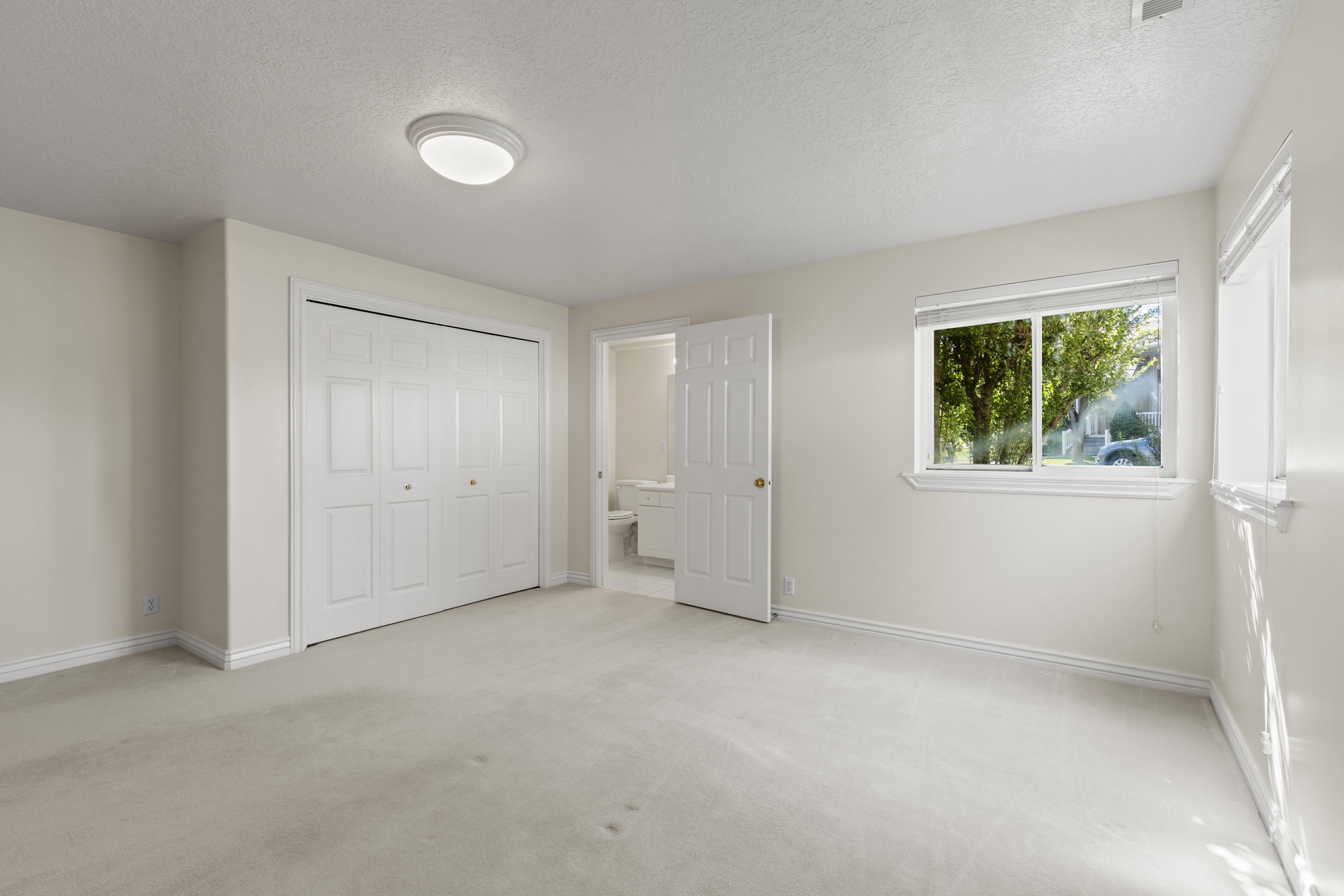 Unfurnished bedroom with a textured ceiling, light colored carpet, a closet, and ensuite bathroom