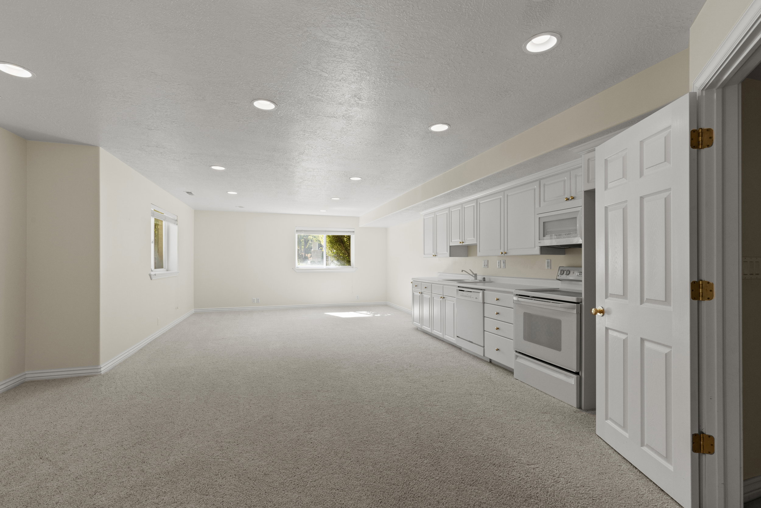 Kitchen featuring white appliances, white cabinets, light countertops, light carpet, and recessed lighting
