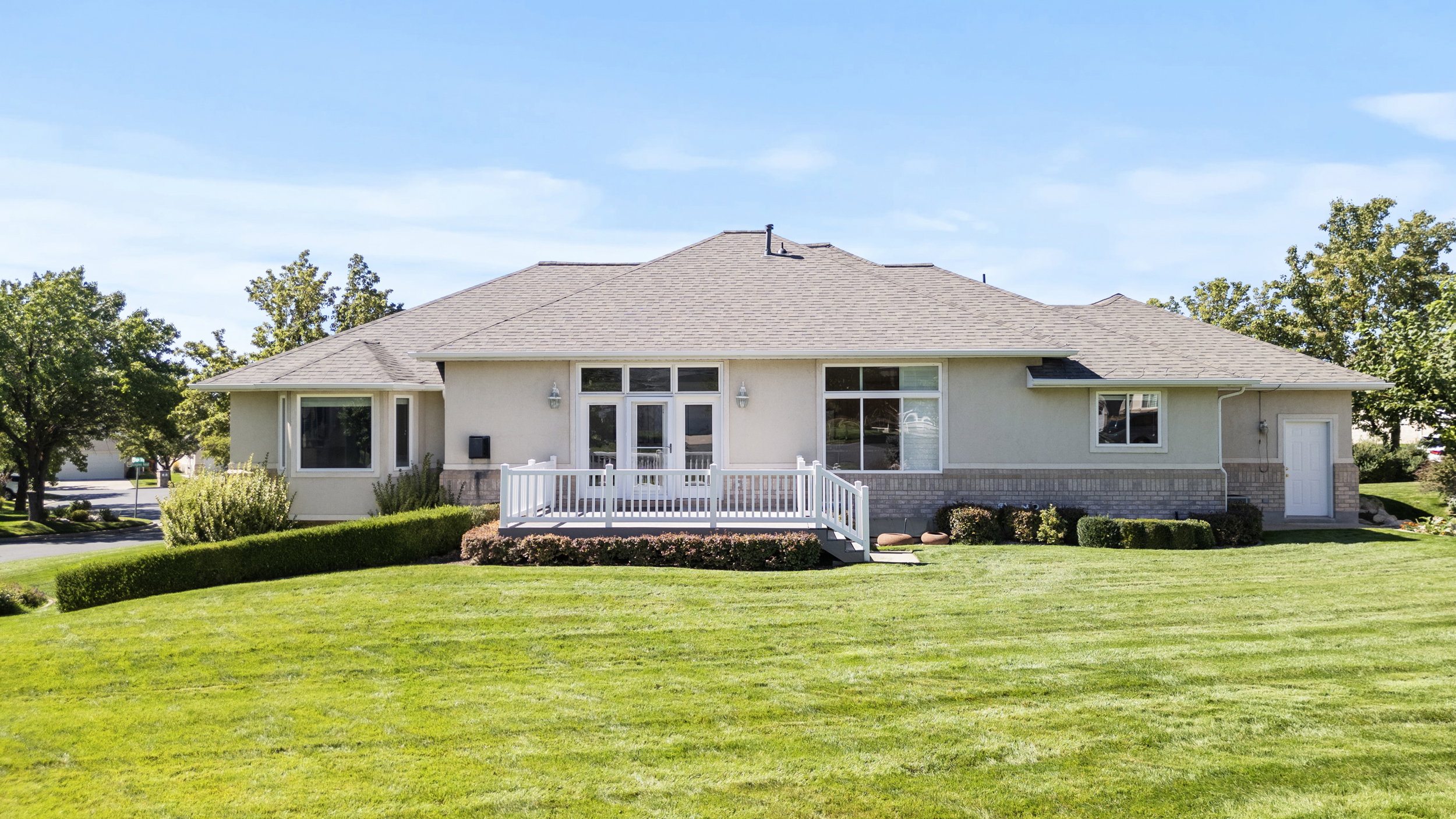 Rear view of house with brick siding, a lawn, a shingled roof, and stucco siding